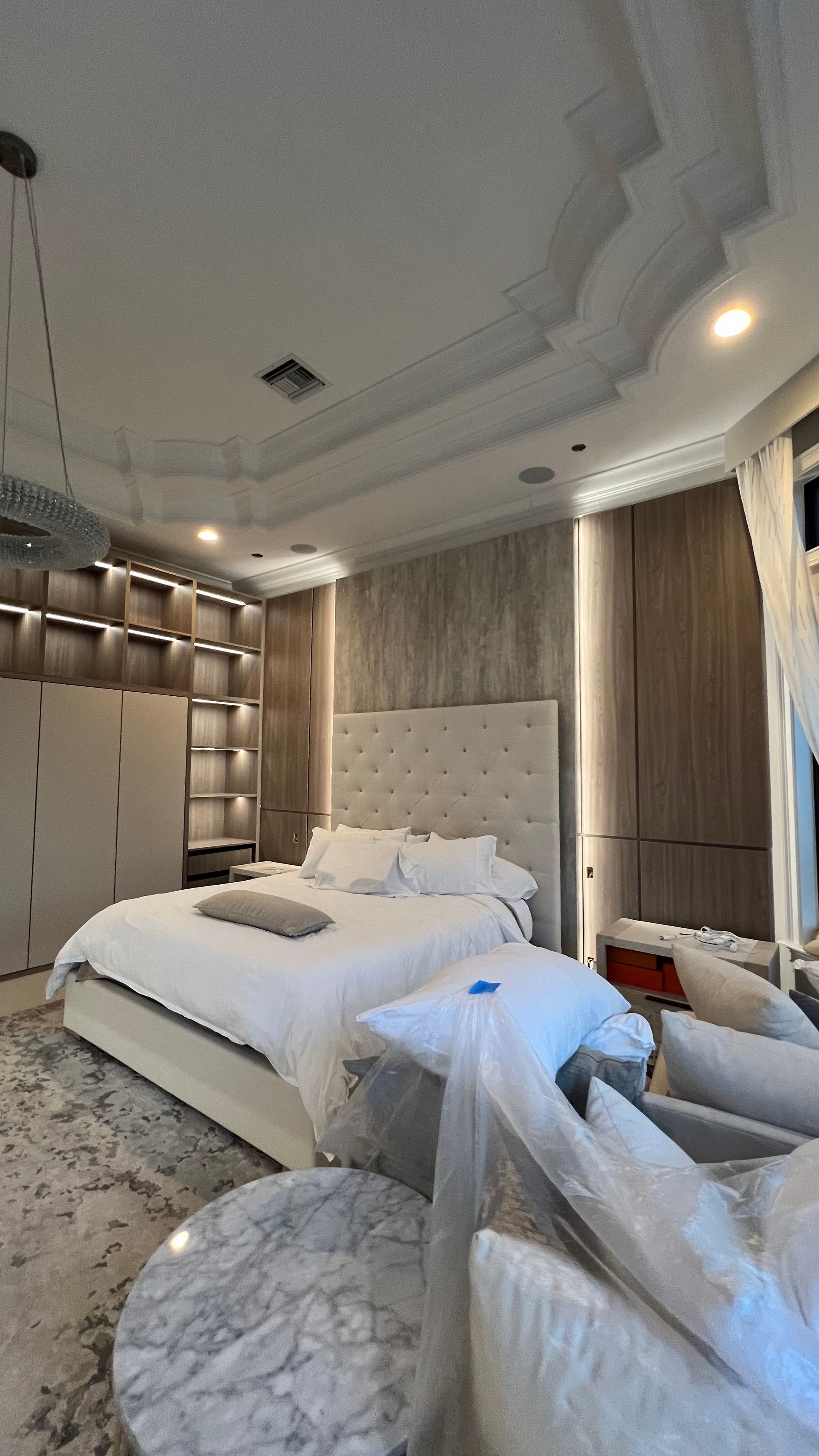 A luxurious bedroom featuring a king-size bed, a large walk-in closet, a marble coffee table, and soft ambient lighting.