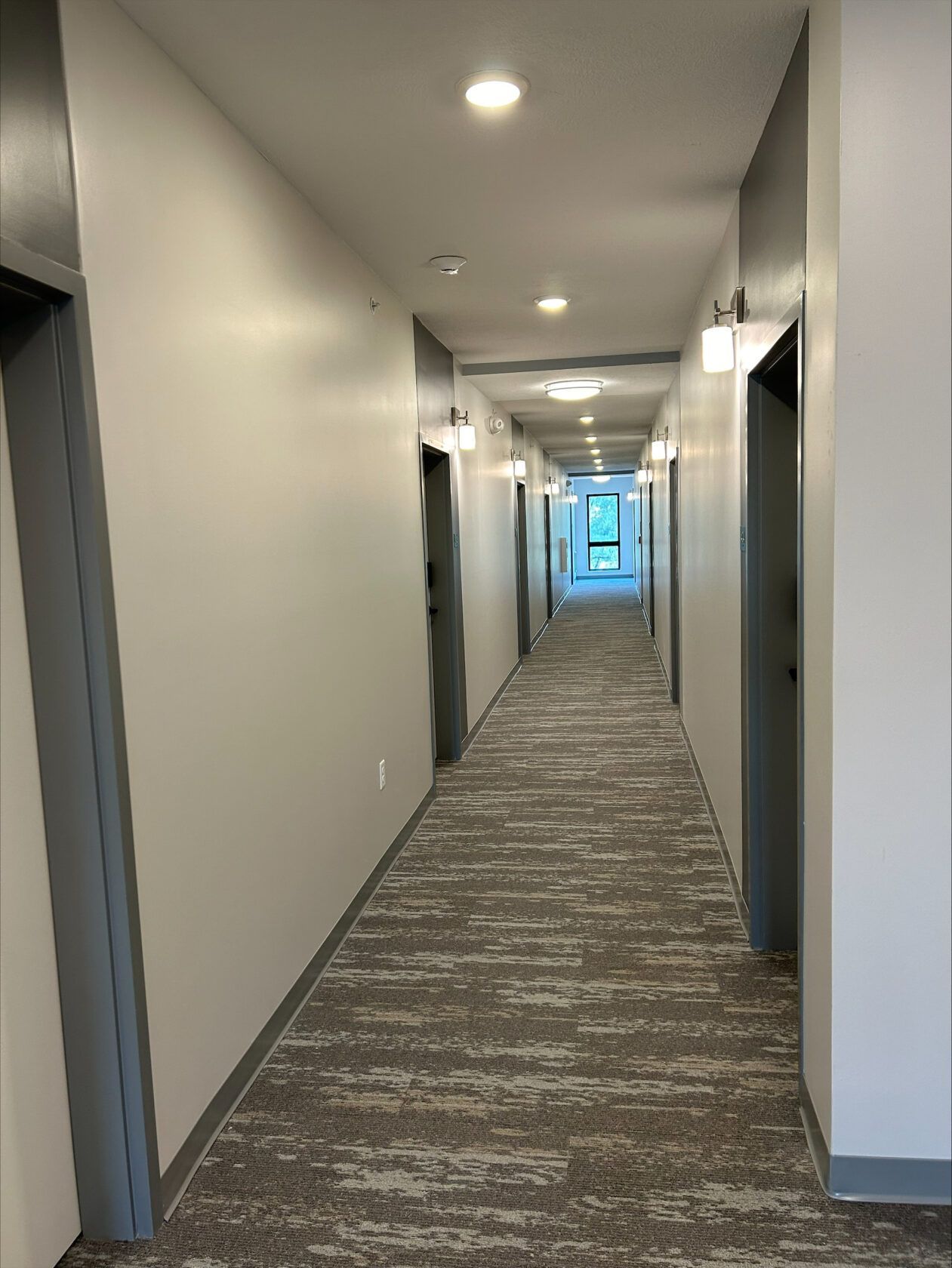 A long hallway with a carpeted floor and white walls.