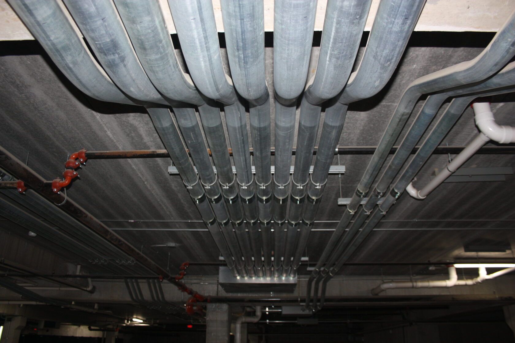 A bunch of pipes are hanging from the ceiling of a building