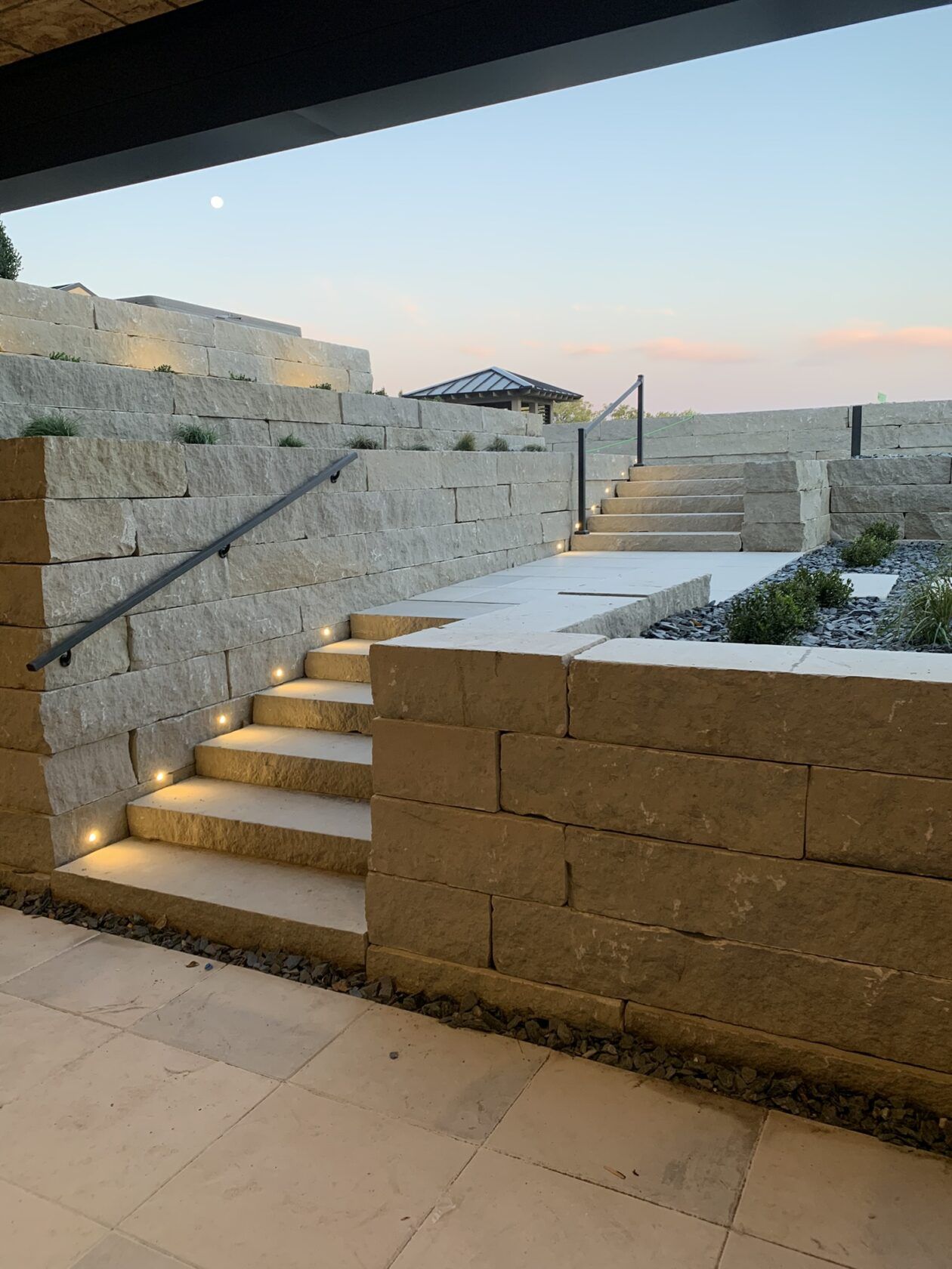 A stone wall with stairs leading up to it and a gazebo in the background.