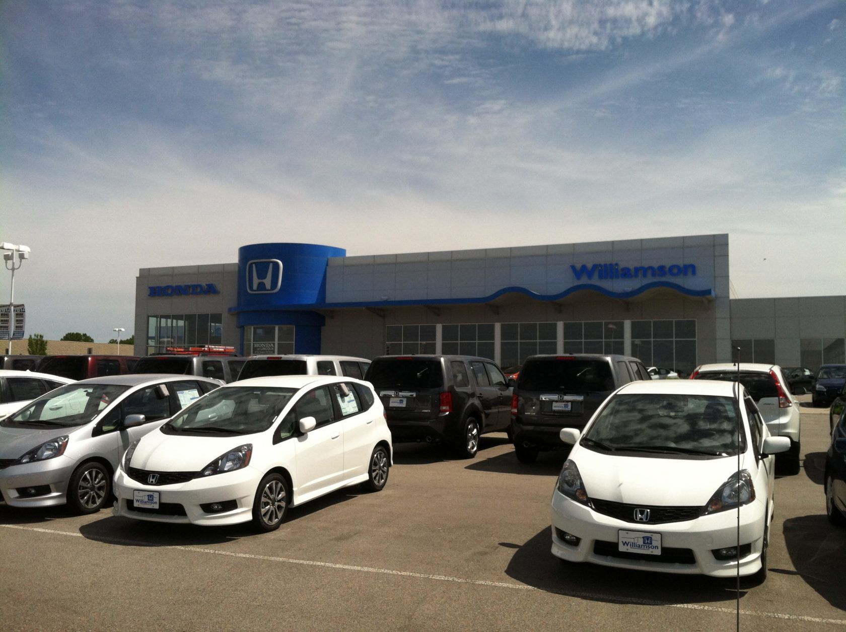 A lot of cars are parked in front of a honda dealership