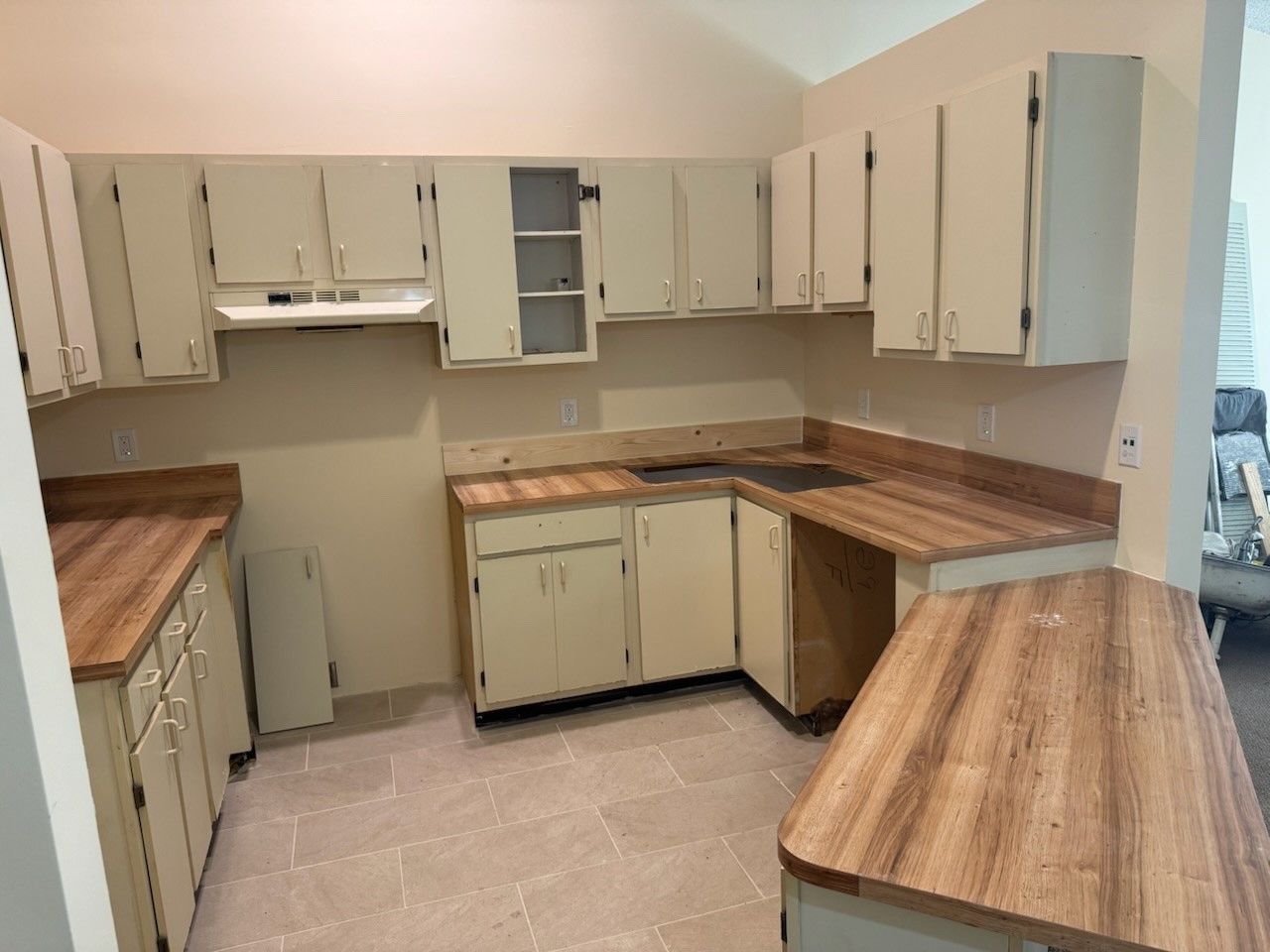 Before image kitchen with white cabinets and wooden counter tops.