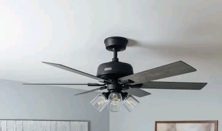 Black ceiling fan with five blades and three light fixtures.