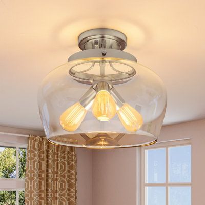 A ceiling light with a clear glass shade is hanging from the ceiling in a room.