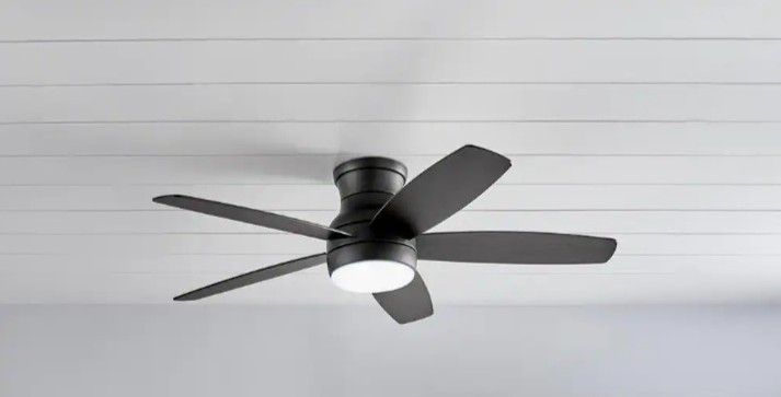 Black ceiling fan with light installed on a white plank ceiling.