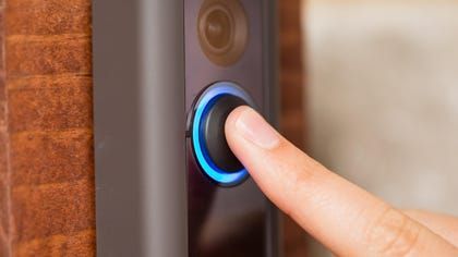 A person is pressing a button on a doorbell.