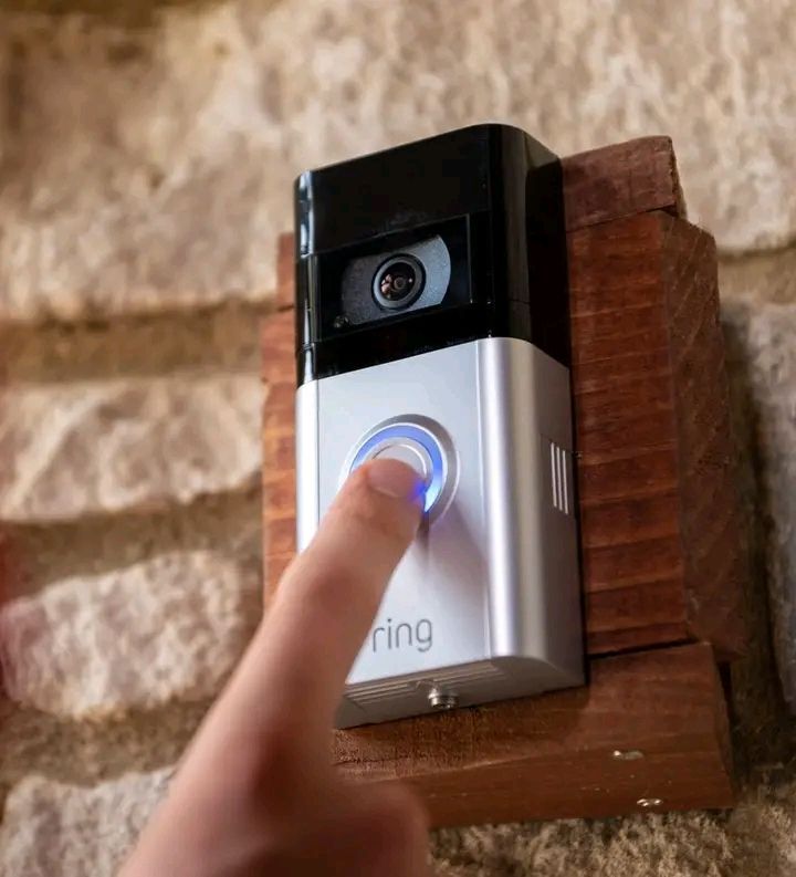 A picture of a Ring doorbell mounted on wood attached to a stone exterior