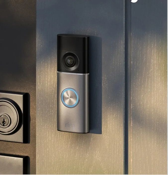 Smart doorbell camera with blue-lit button mounted on a metallic door frame.