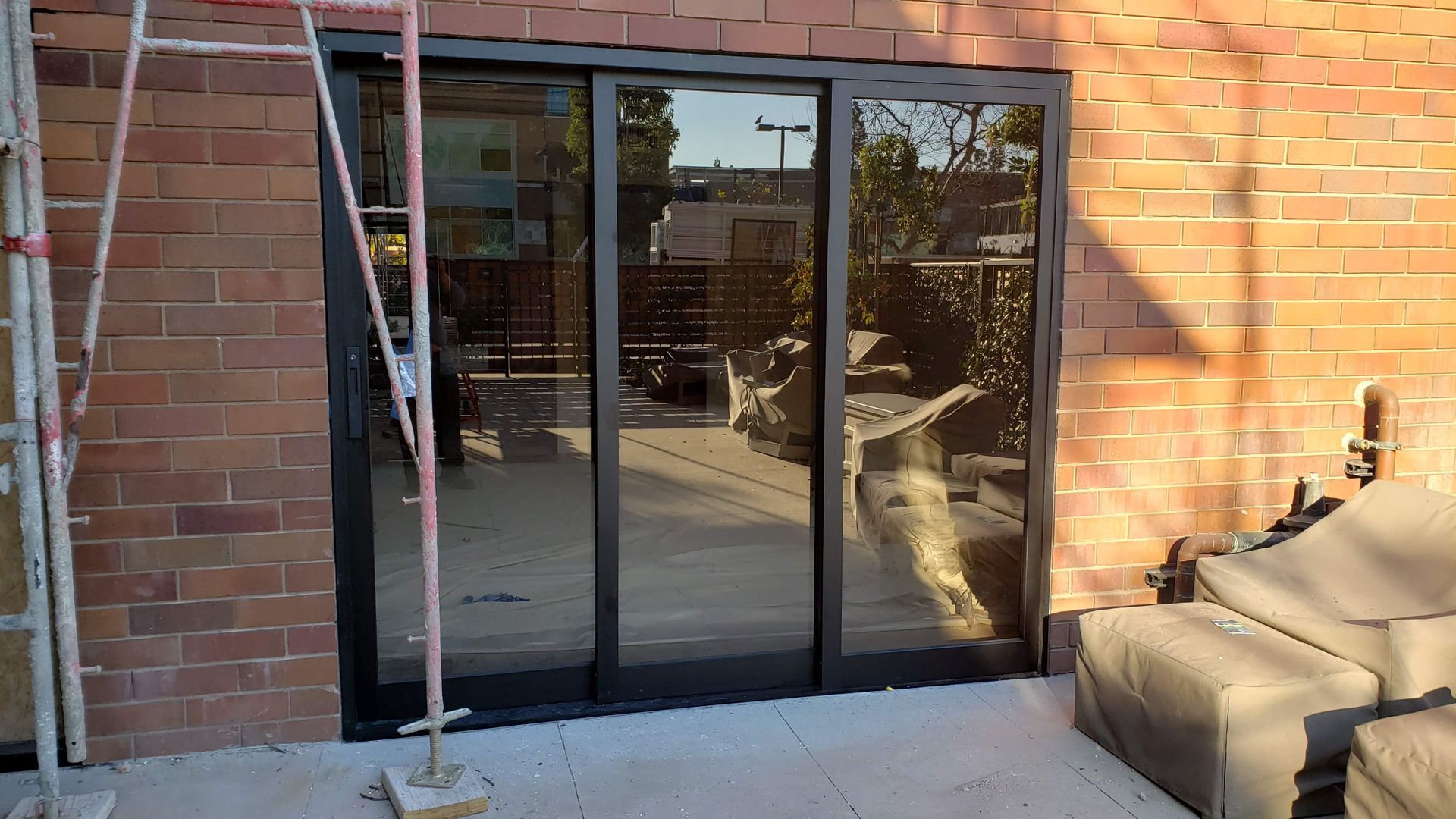 A sliding glass door is being installed on a brick building.