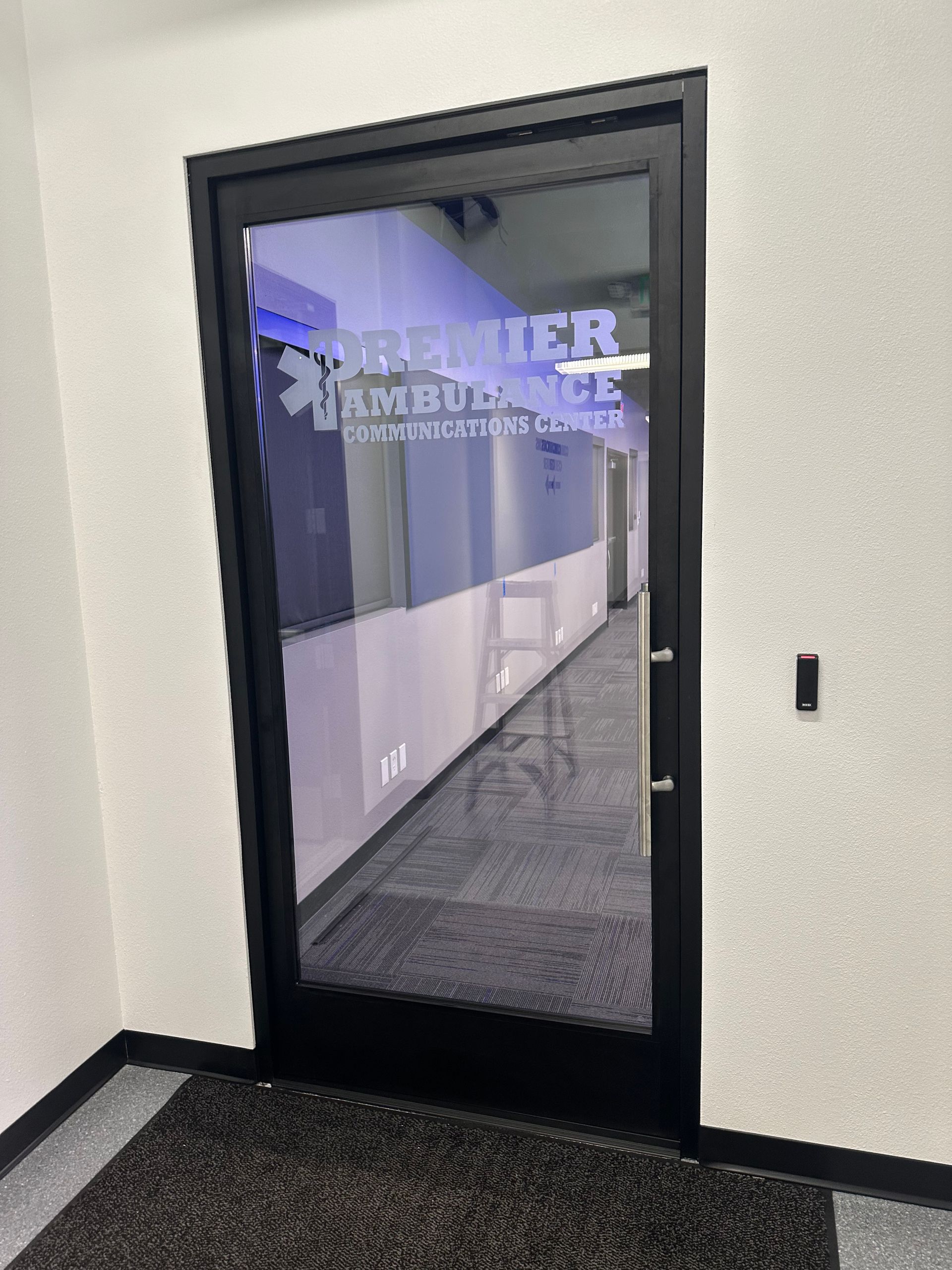 A hallway with a glass door and a sign on the wall.