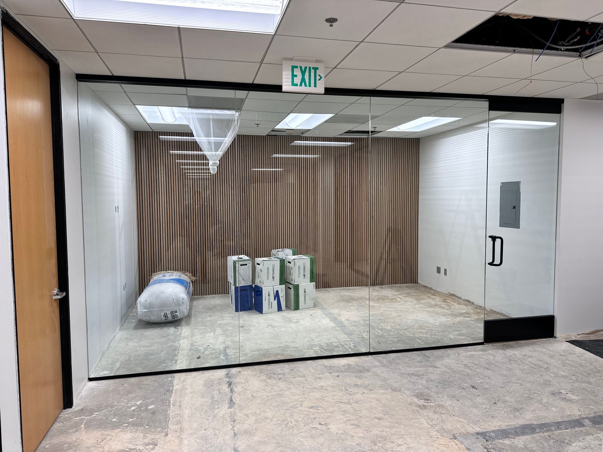 An empty room with a green exit sign on the ceiling