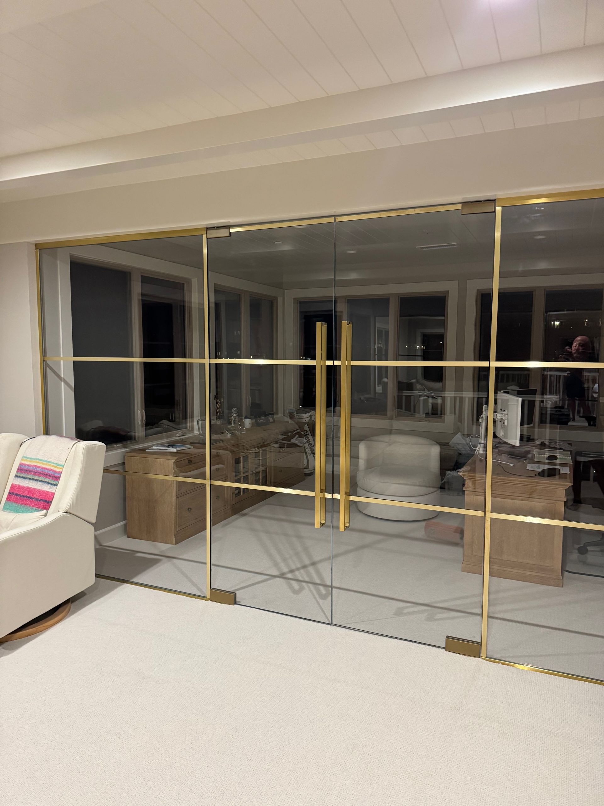 Glass doors with gold framing and handles, white interior, soft rug, and sofa.