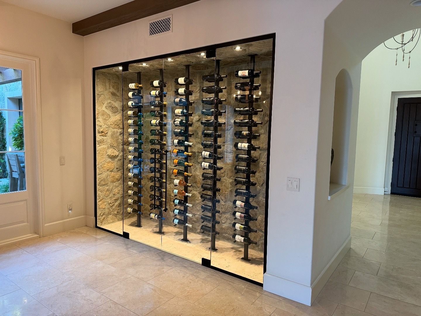Wine storage display with glass doors, stone backing, and bottles displayed.