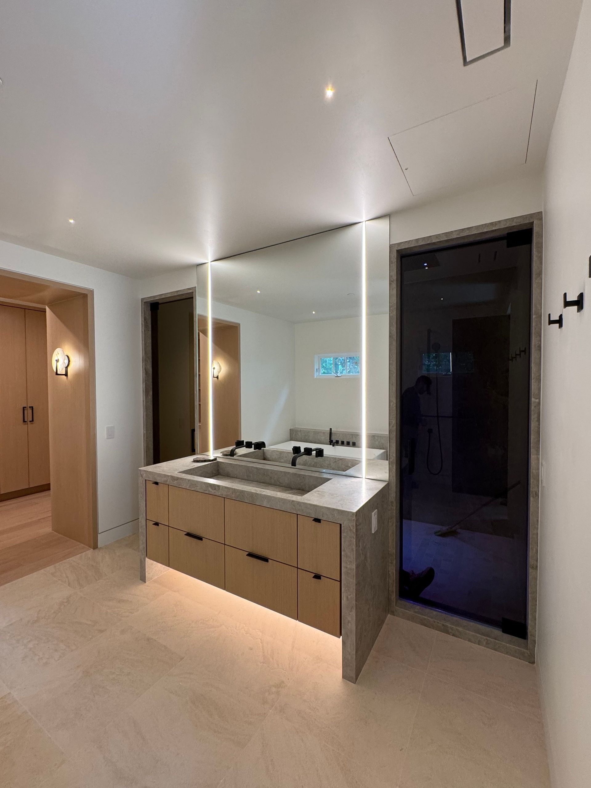 Modern bathroom with double vanity, large mirror, and glass shower enclosure.