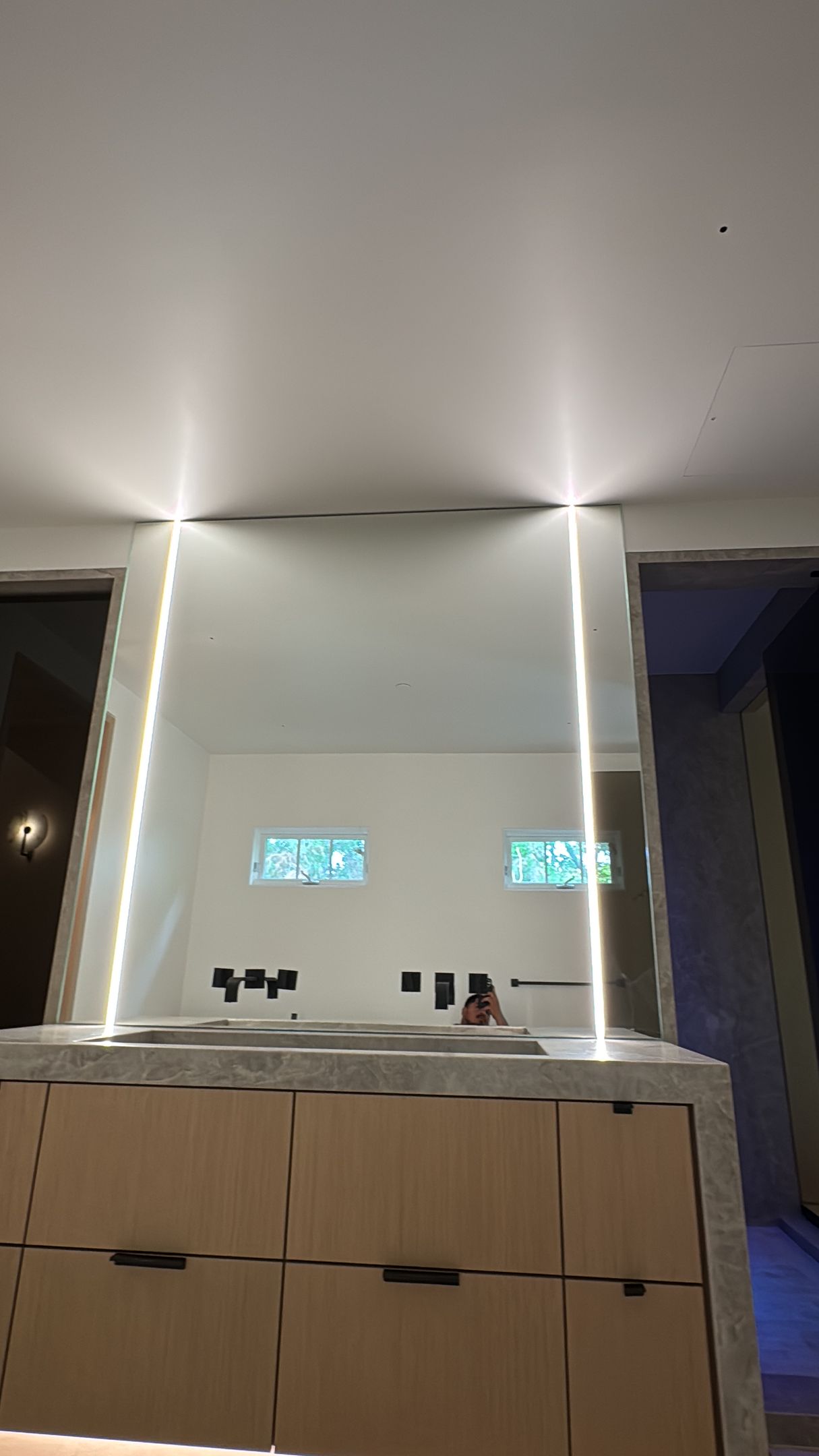 Modern kitchen with light strips framing a white wall, cabinets, and a countertop.