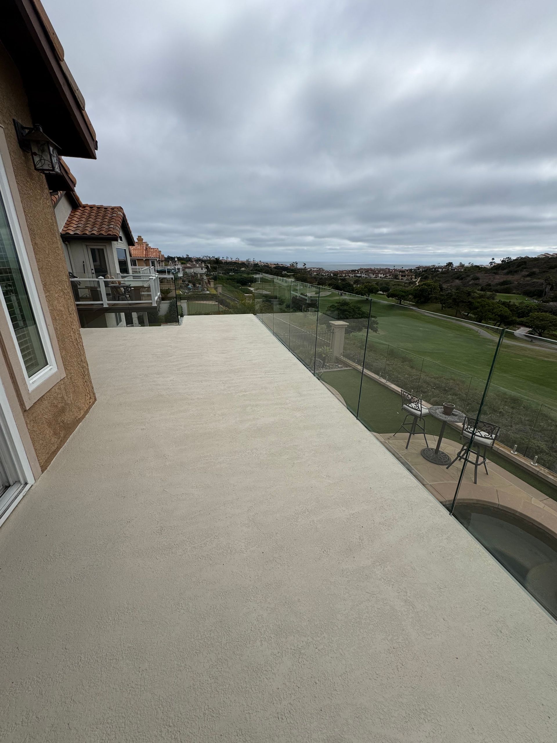 View from a building's balcony overlooking a golf course and distant cityscape under a cloudy sky.