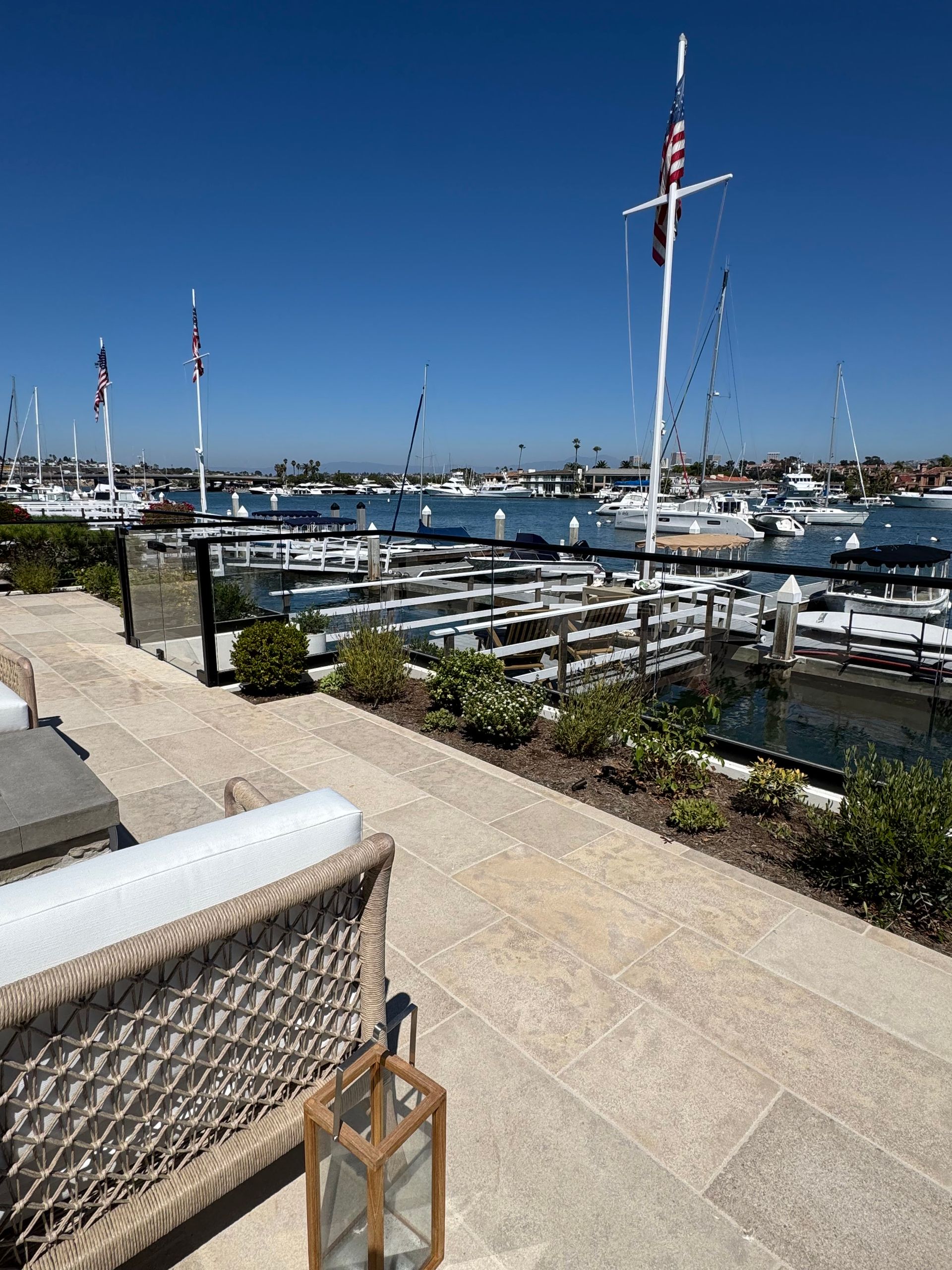 Patio with a view of a harbor filled with boats and American flags on a sunny day.