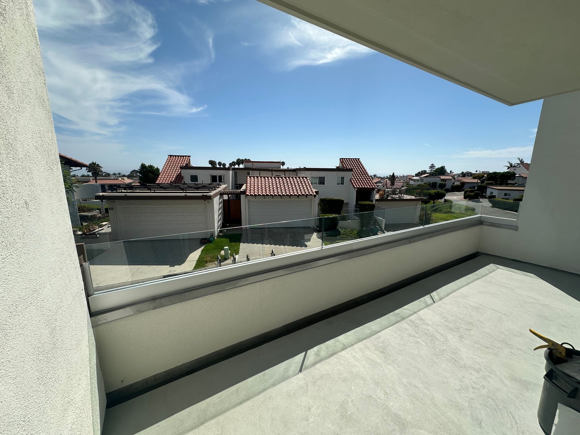 View from a balcony overlooking several houses with red roofs under a blue sky.