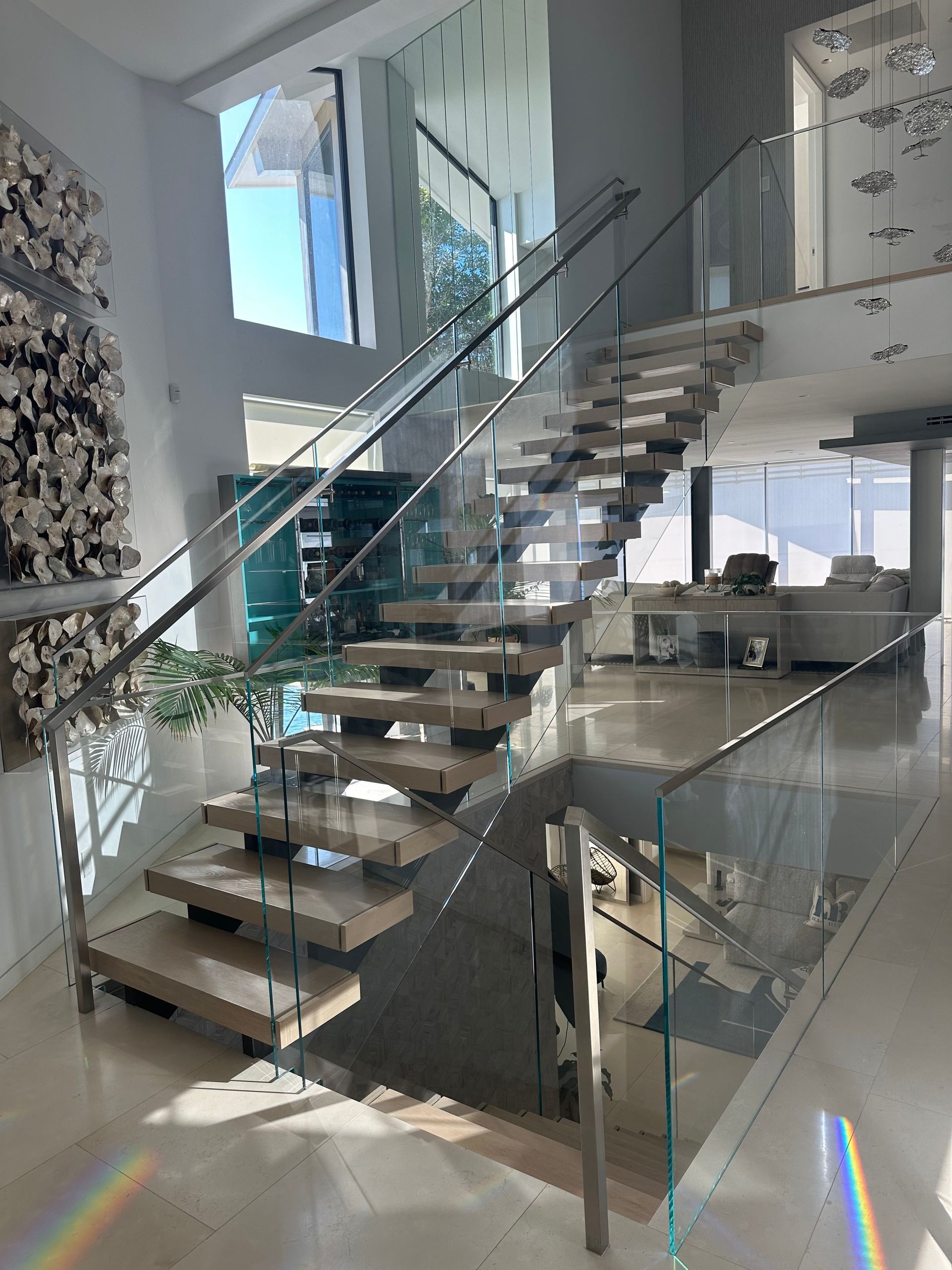 Modern staircase with glass railings and wood steps in a bright, spacious home.
