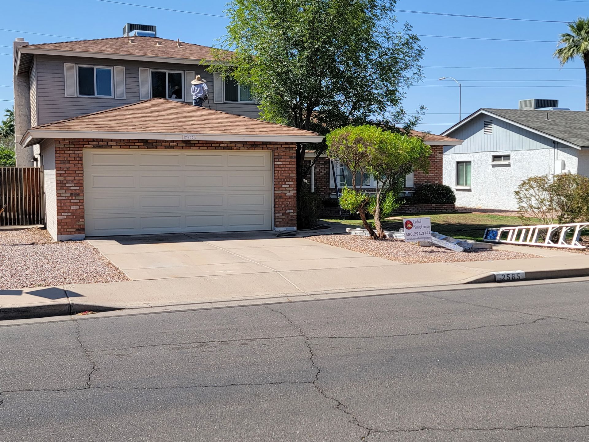 A house with a white garage door is sitting on the side of the road.