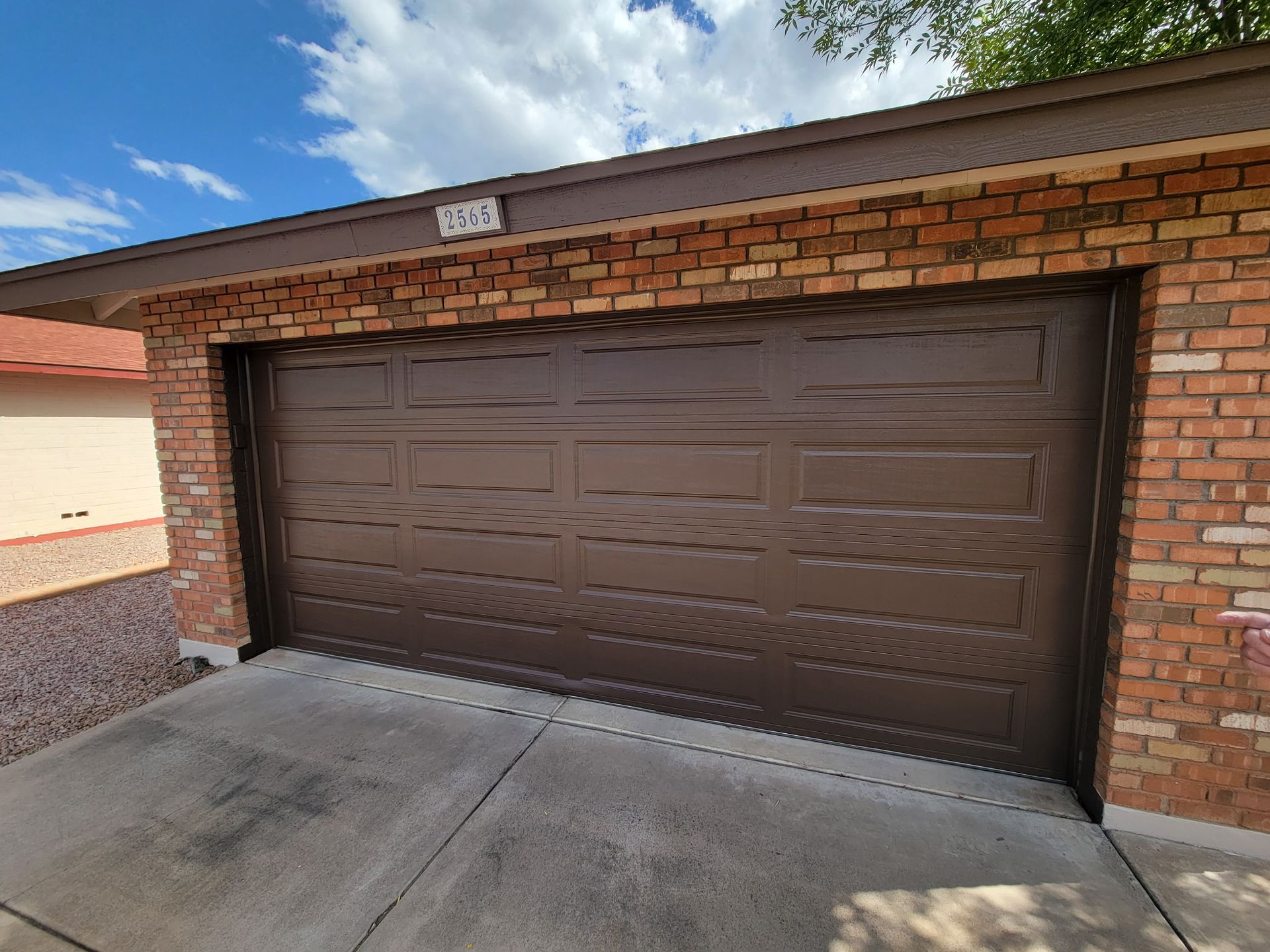 A brown garage door is sitting in front of a brick building.