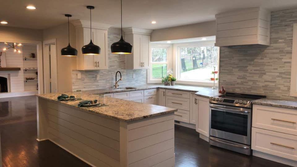 a kitchen with white cabinets , granite counter tops , stainless steel appliances and a large island .