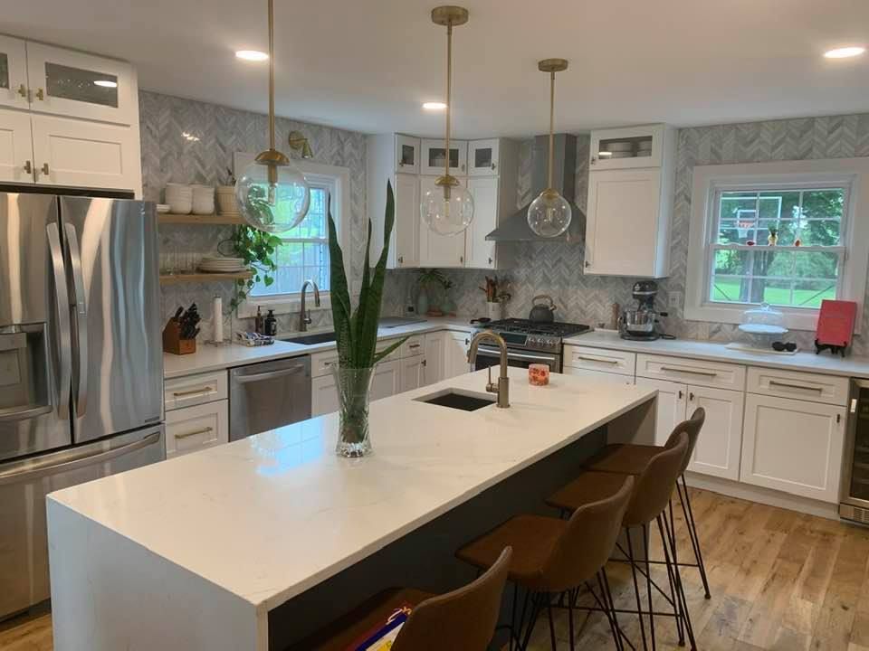 a kitchen with white cabinets and stainless steel appliances and a large island .