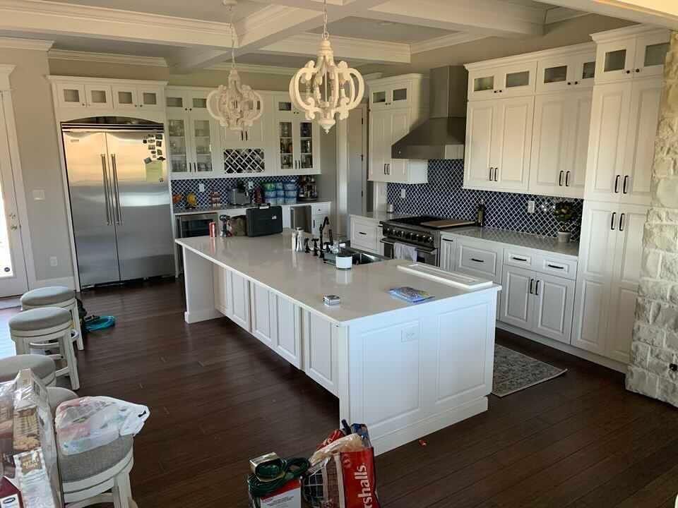 a kitchen with white cabinets , stainless steel appliances , and a large island .