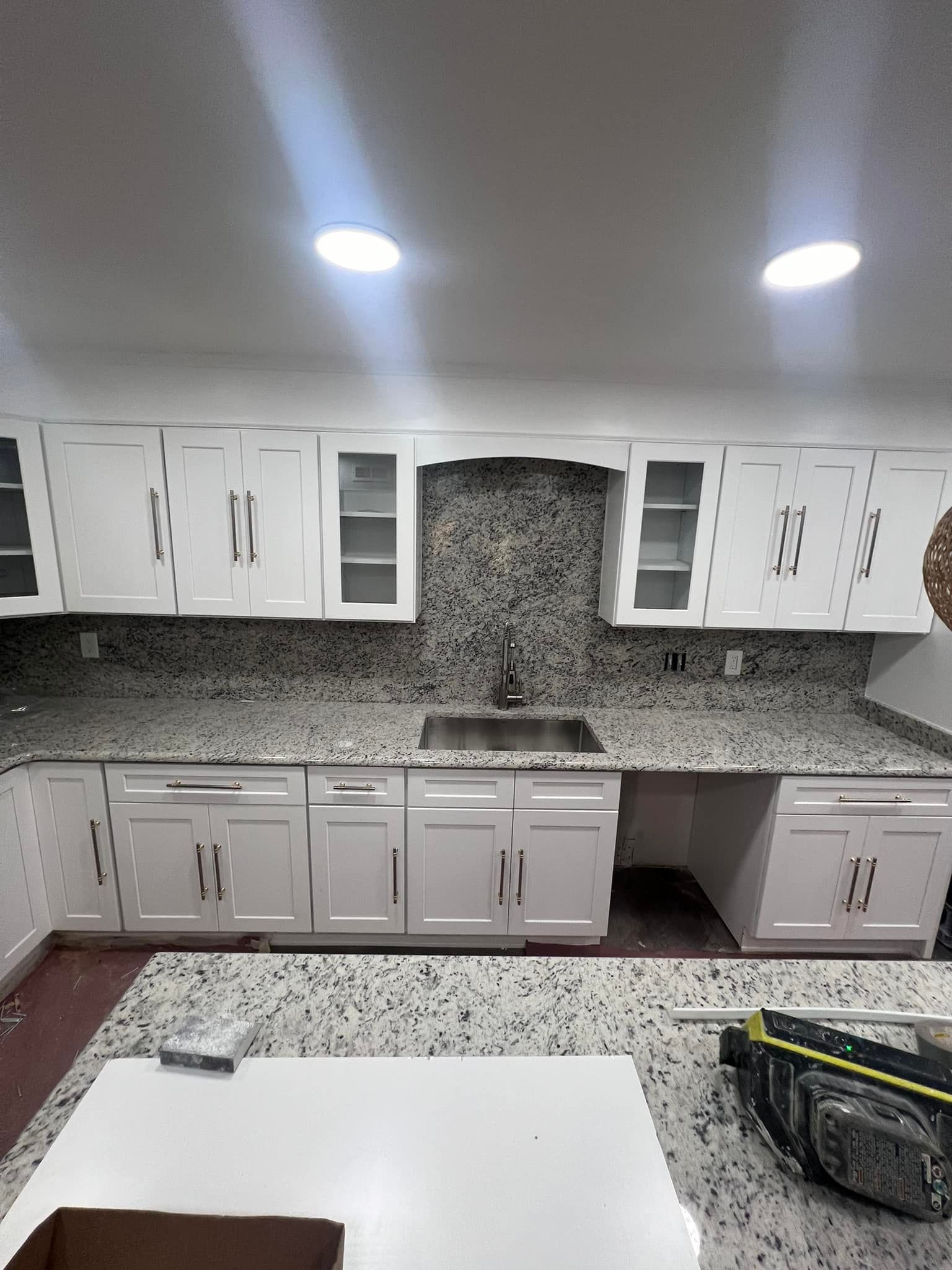 a kitchen with granite counter tops , white cabinets and a sink .