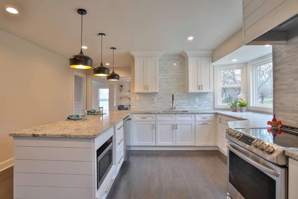 a kitchen with white cabinets , granite counter tops , stainless steel appliances and a large island .
