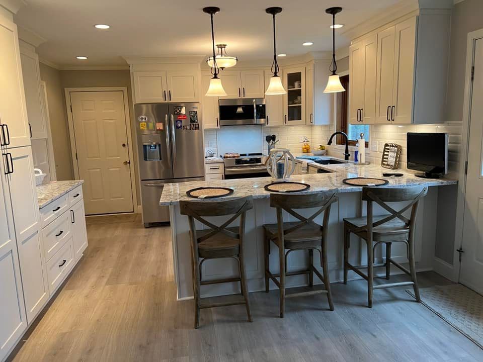 a kitchen with white cabinets , stainless steel appliances , and a large island .