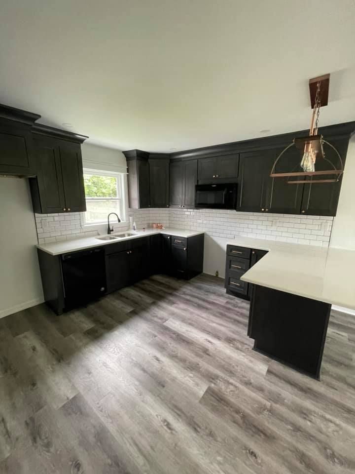 a kitchen with black cabinets and white counter tops .