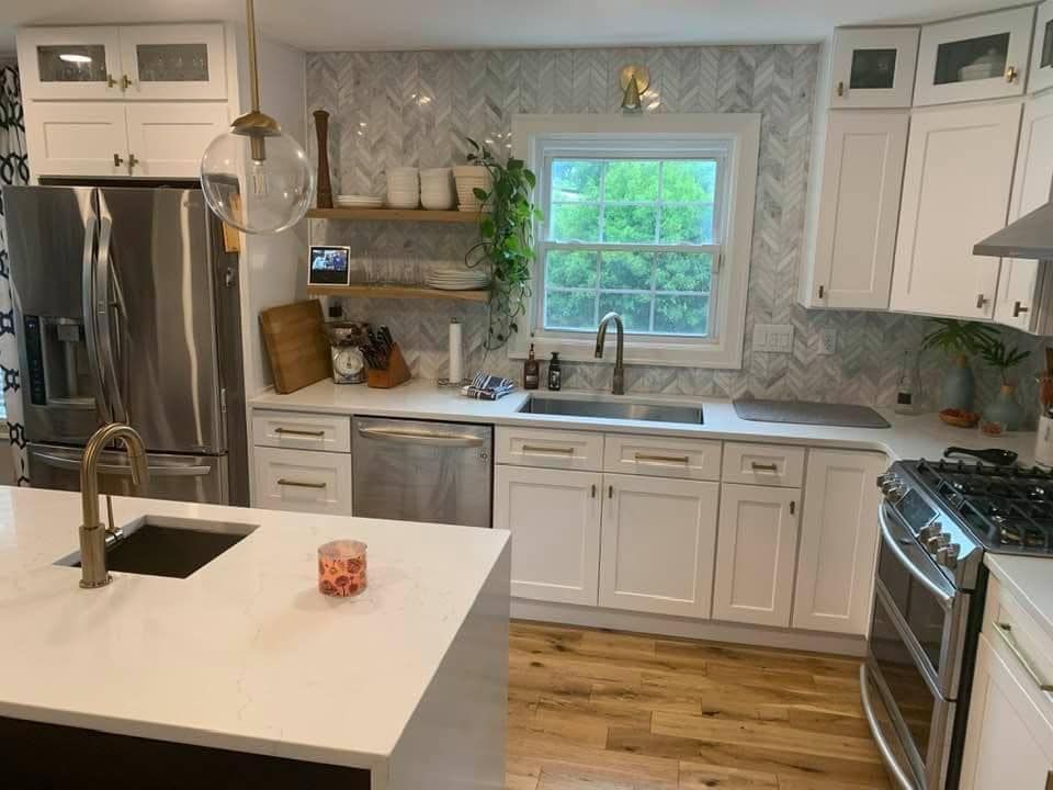 a kitchen with white cabinets , stainless steel appliances , a sink , and a window .