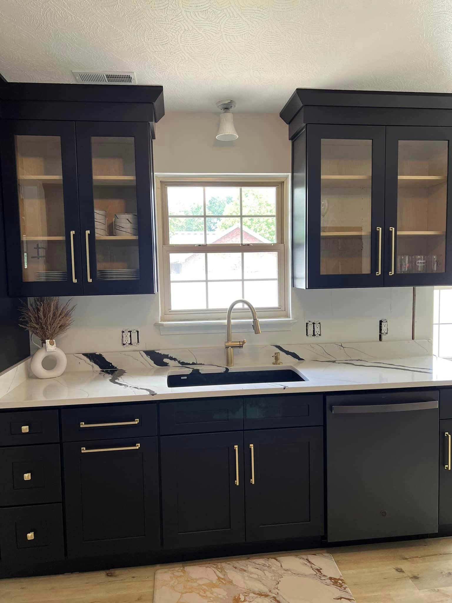 a kitchen with black cabinets and a sink and a window
