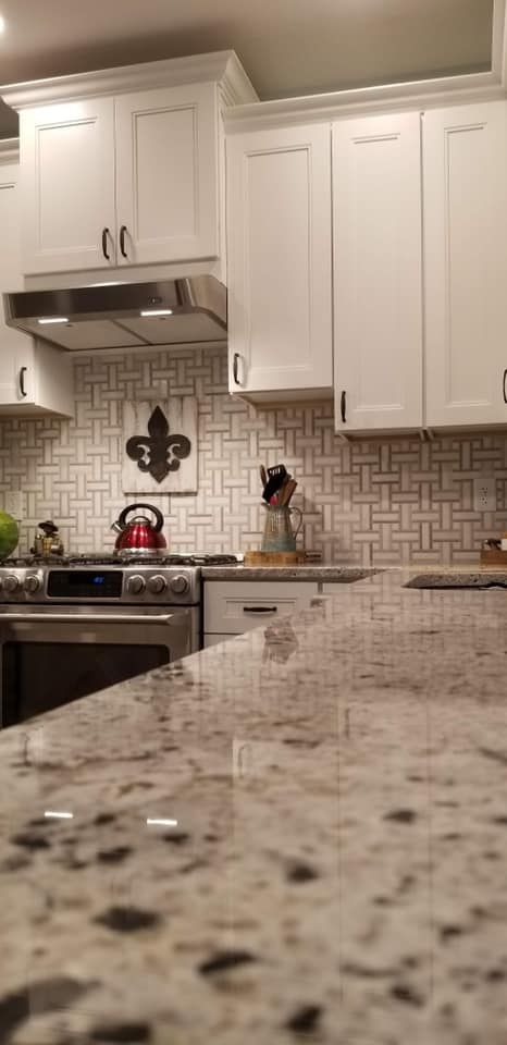 a kitchen with white cabinets and granite counter tops .