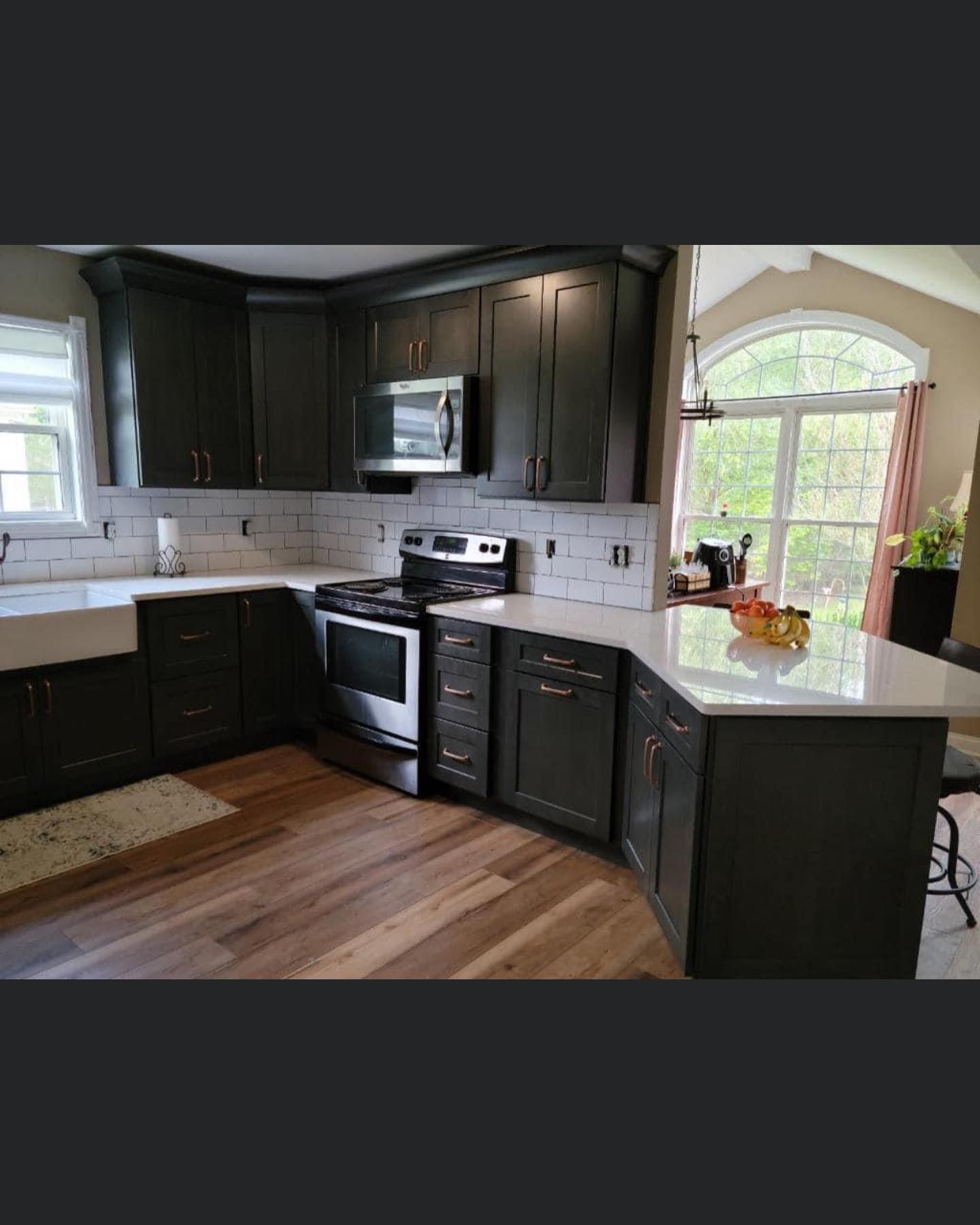 a kitchen with black cabinets , stainless steel appliances , a sink , and a window .