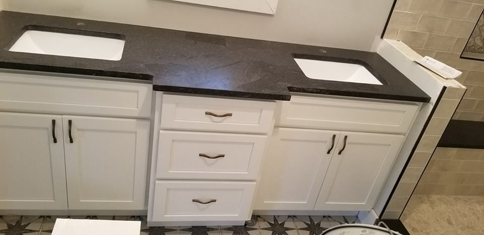 a bathroom with two sinks and white cabinets .