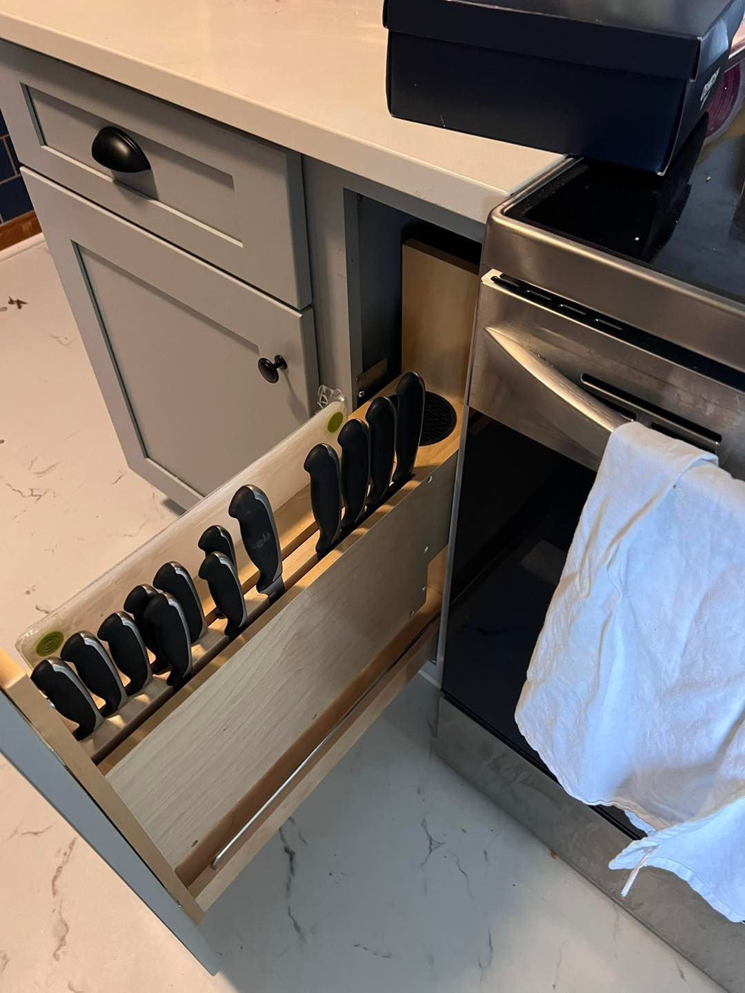 a kitchen with a drawer filled with knives next to a stove .