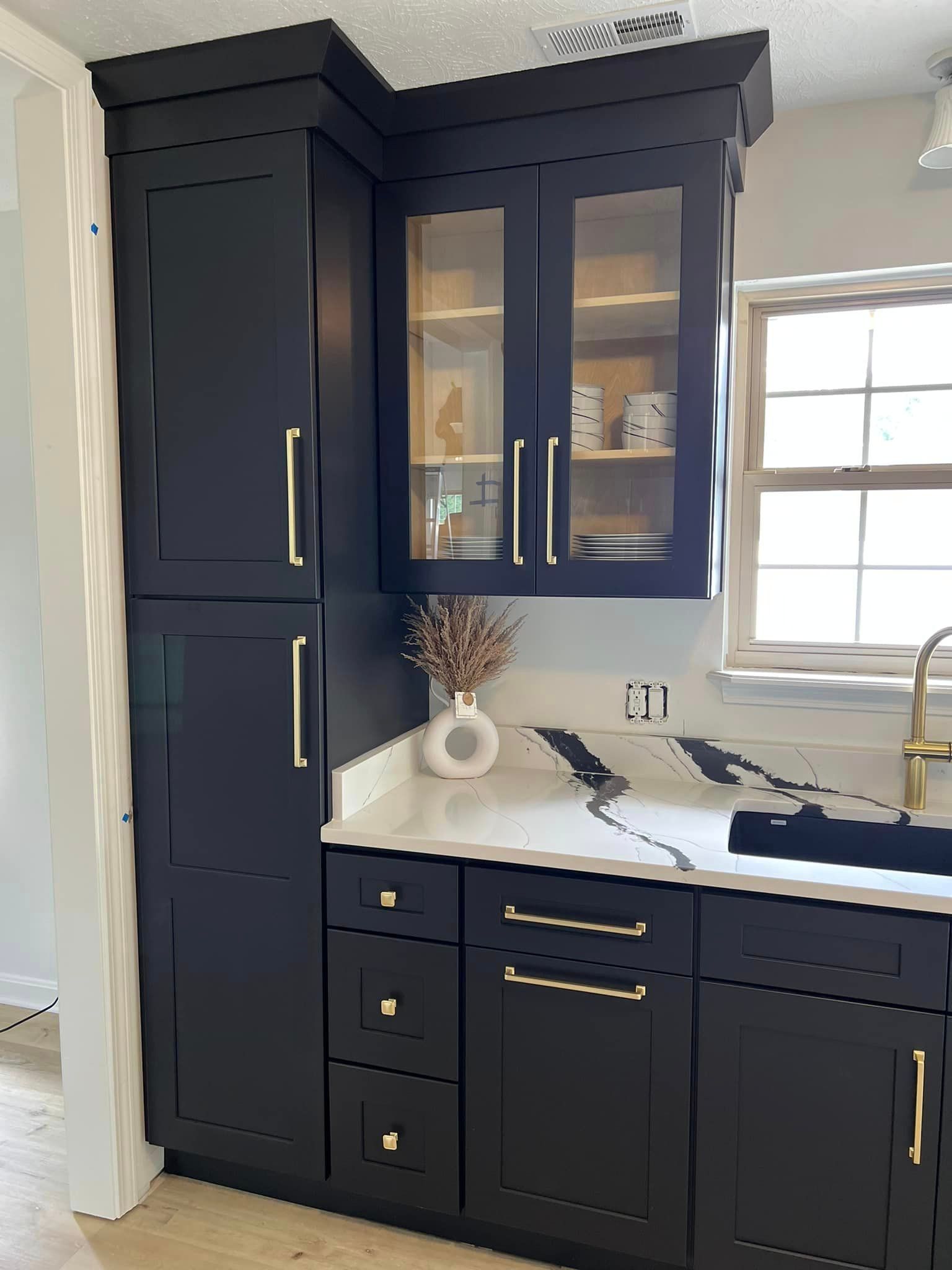 a kitchen with black cabinets , a sink , and a window .