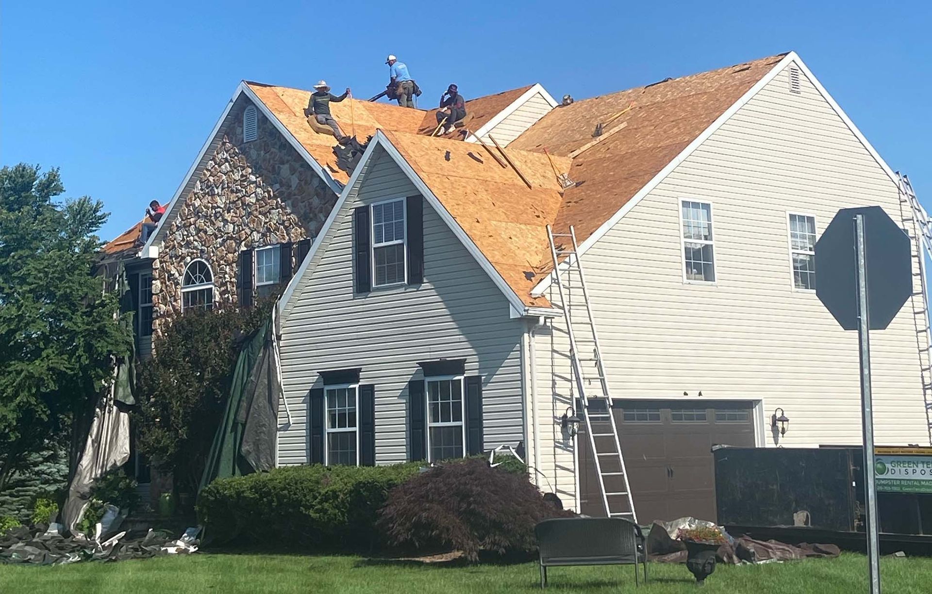 Roofers working on a house with a partly new roof; sunny day.