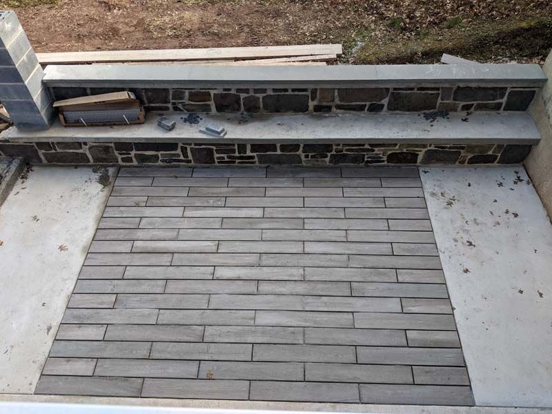 Concrete steps with gray brick-like pavers and a retaining wall under construction.