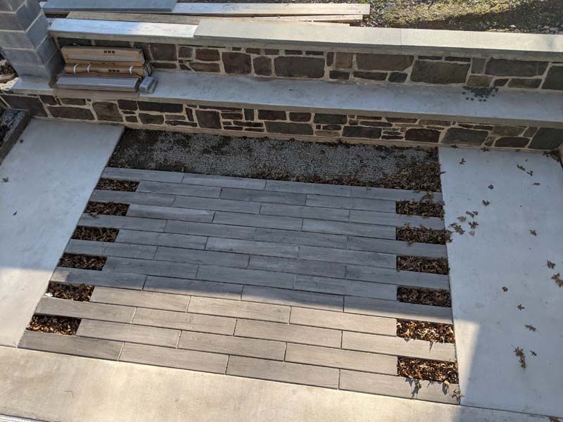 Stone patio with gray pavers and accents of exposed aggregate and stone walls.