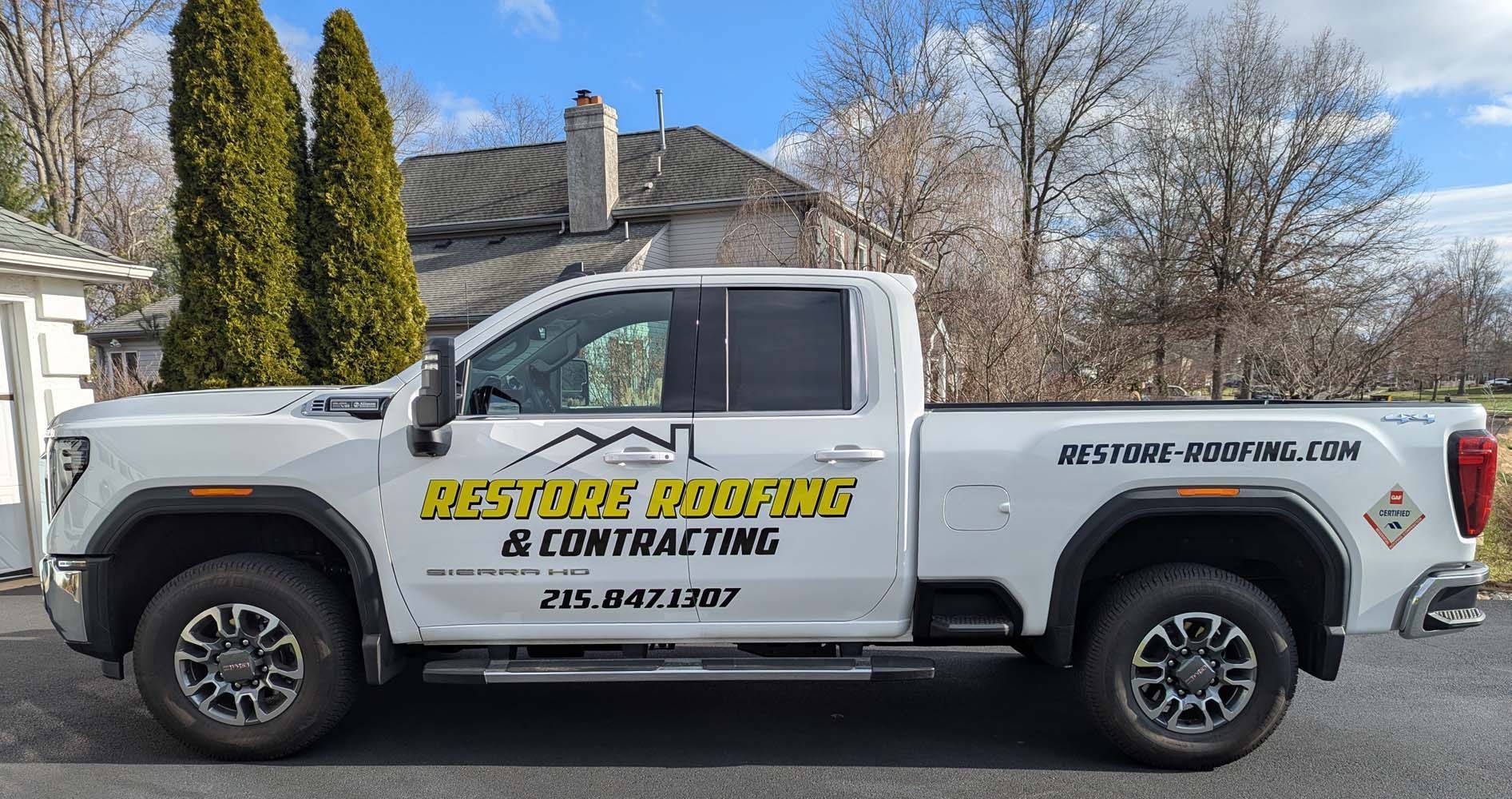 White Restore Roofing & Contracting truck parked in front of a house.
