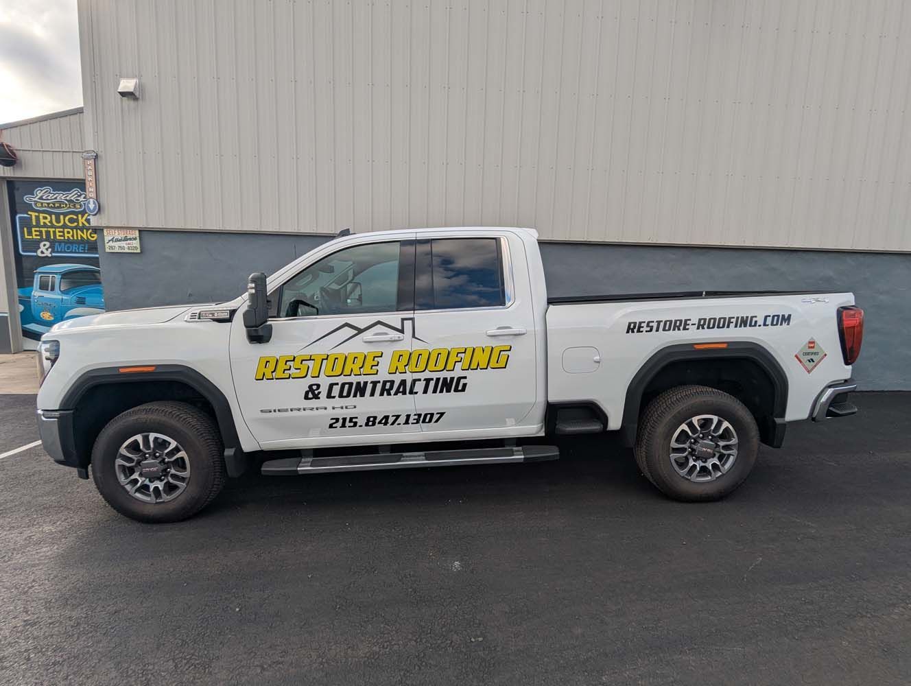 White work truck with company logo parked outside a building.