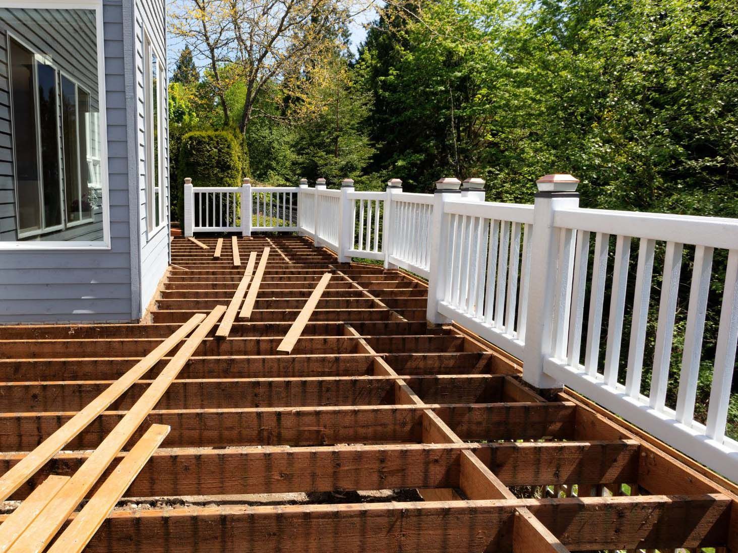 Deck under construction with exposed framing. White railing in place.