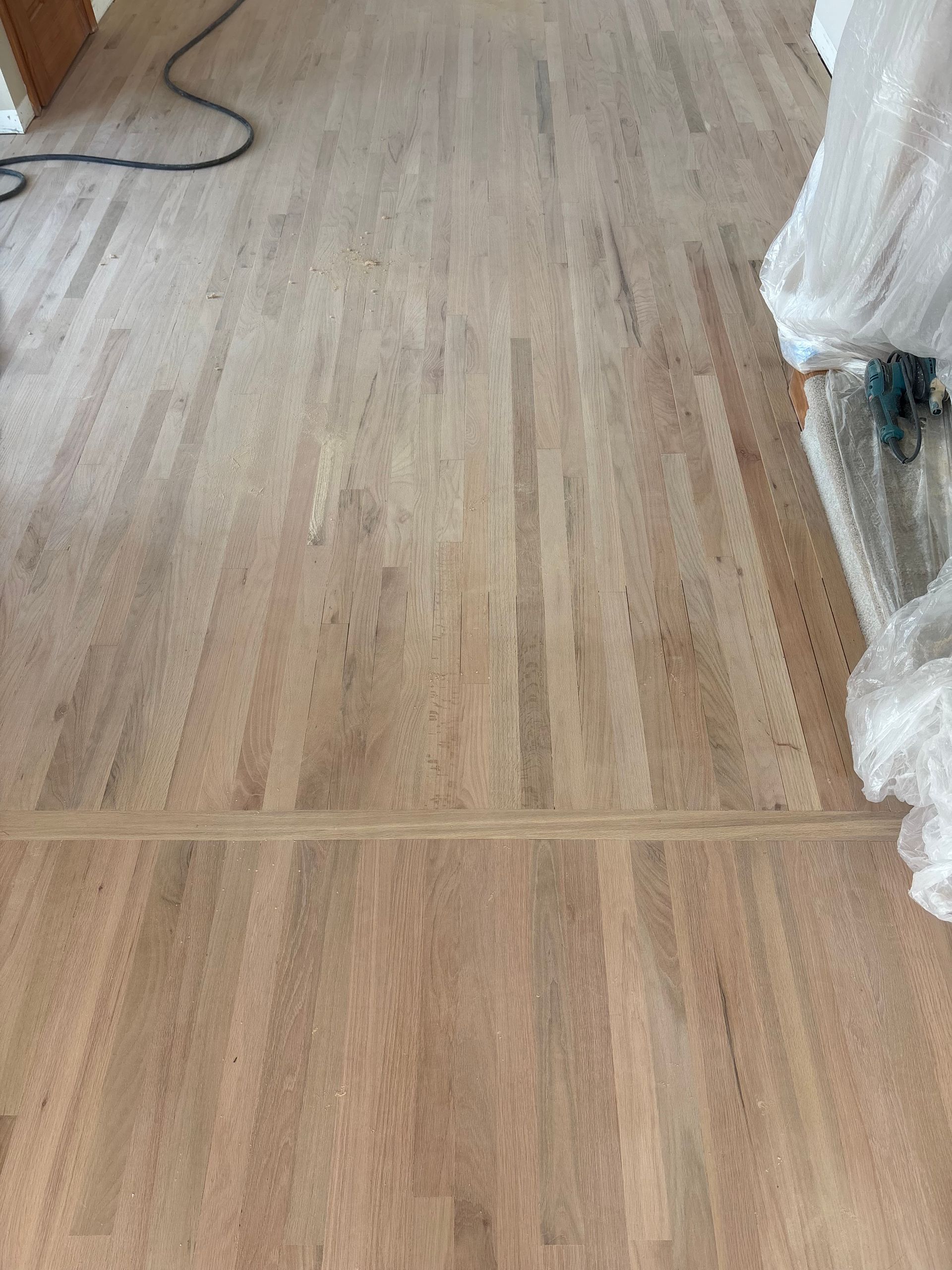 Empty light wood floor with a white-draped object at the right edge