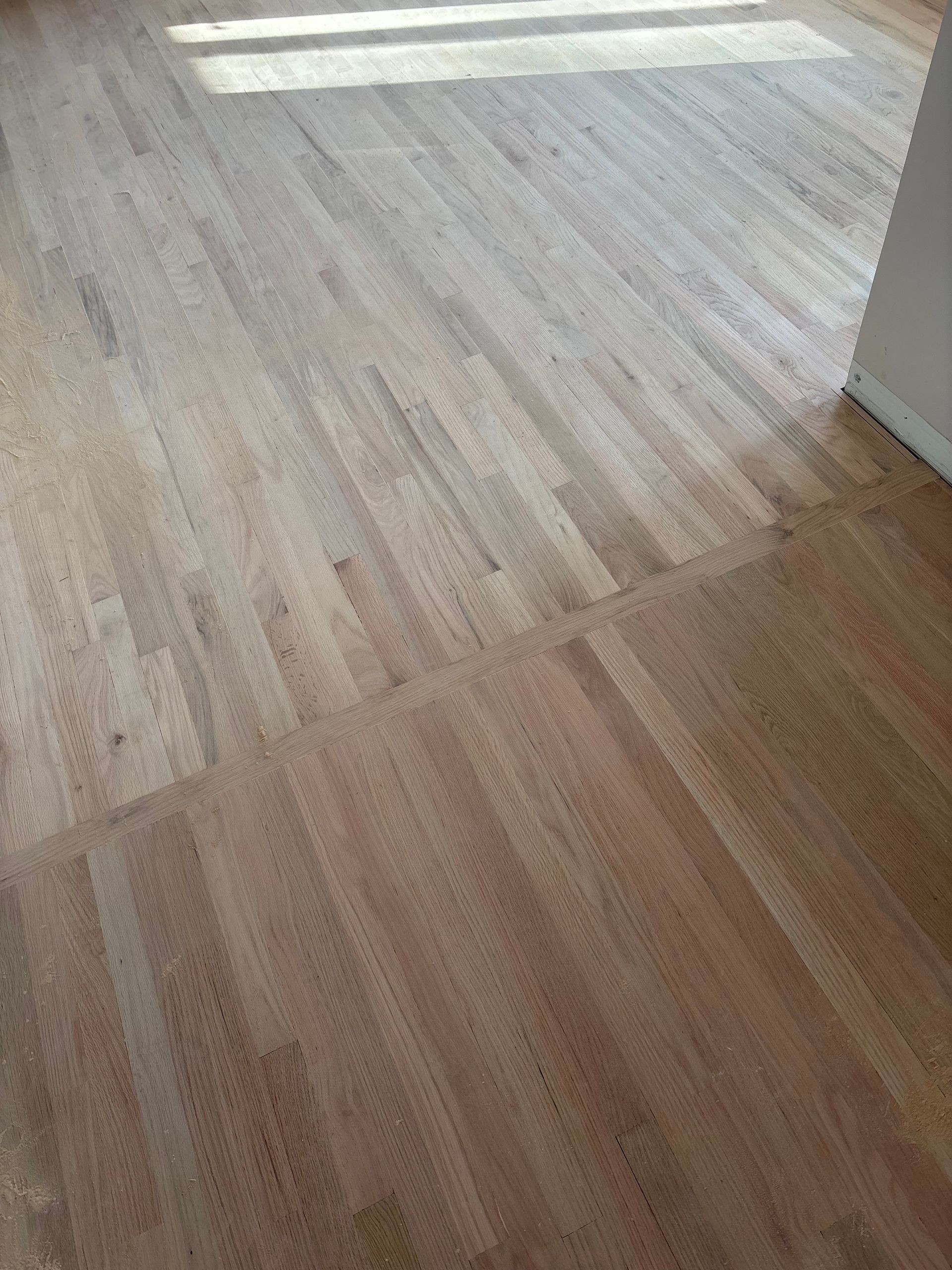 Sunlit wooden floor with light-colored planks in an empty room