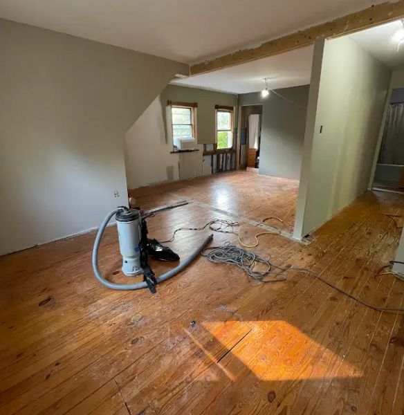 Room renovation: Dusty wooden floors, vacuum cleaner, exposed beams, and light green walls.