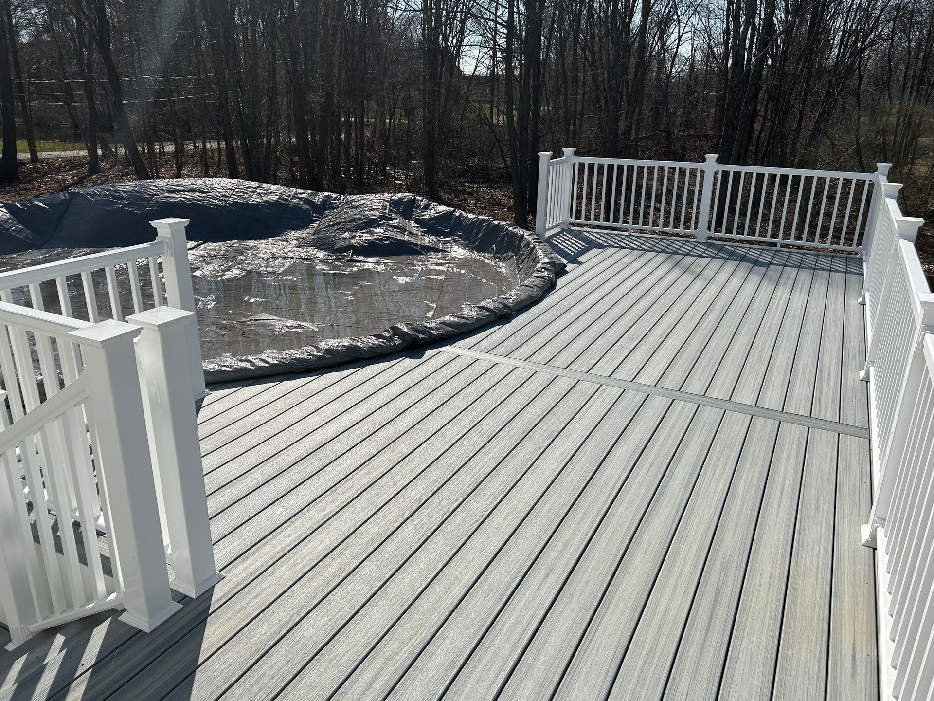 Grey composite deck with white railings, overlooking a muddy pond.