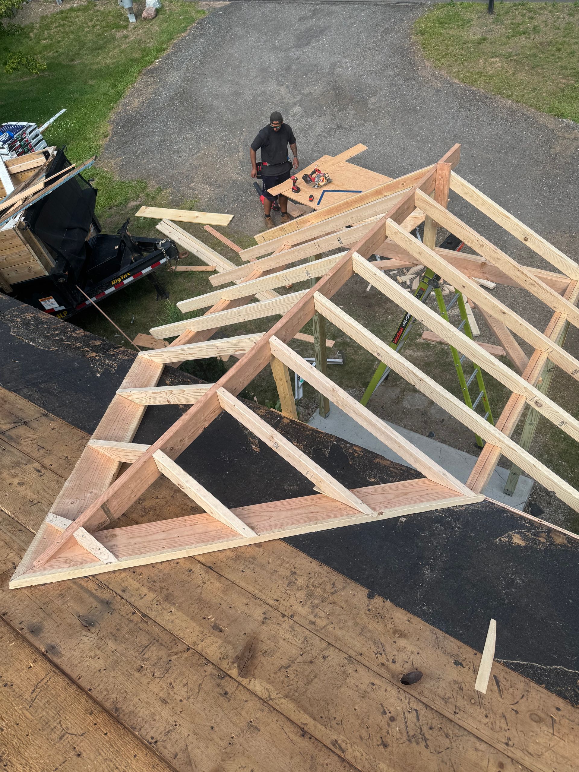 Construction worker on a roof building a wooden frame for a gable roof.